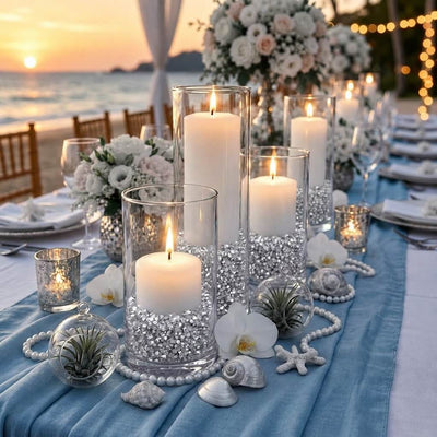 Lit white candles in glass vases filled with silver faux diamond gems on a blue beach table runner - thumbnail number 4