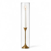 A lit white taper in a gold holder with a 4"x20" chimney glass candle shade - thumbnail number 3