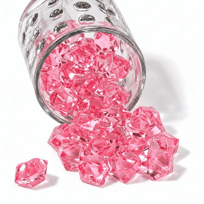 Pink acrylic ice beads spilling out of a textured clear glass jar onto a white background - thumbnail number 1