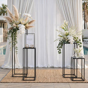 Floral arrangements on black metal stands with a welcome sign at an outdoor event - thumbnail number 4