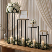 Black metal display stands with floral arrangements, candles, and a welcome sign for a wedding - thumbnail number 5