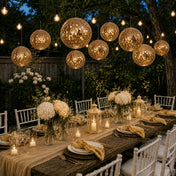 Hanging gold sequin lanterns glowing over a candlelit outdoor dinner party table - thumbnail number 6