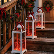 White lanterns filled with red LED fairy lights decorated with red bows on wooden stairs - thumbnail number 9