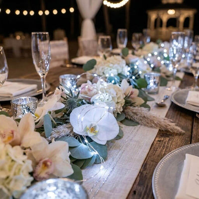 White LED fairy lights draped among floral arrangements and candles on a wedding table - thumbnail number 7