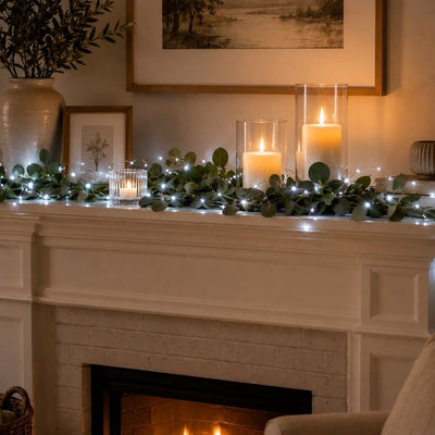 White LED fairy lights draped with greenery and candles on a fireplace mantel - thumbnail number 9