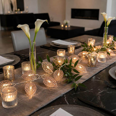 Rose gold leaf string lights with candles and flowers decorating a formal dining table - thumbnail number 7