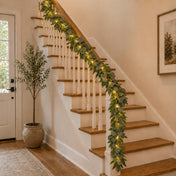Eucalyptus garland with warm white LED string lights wrapped around an indoor staircase railing - thumbnail number 9