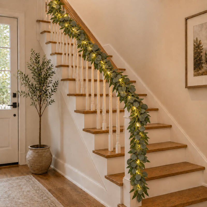 Eucalyptus garland with warm white LED string lights wrapped around an indoor staircase railing - thumbnail number 9
