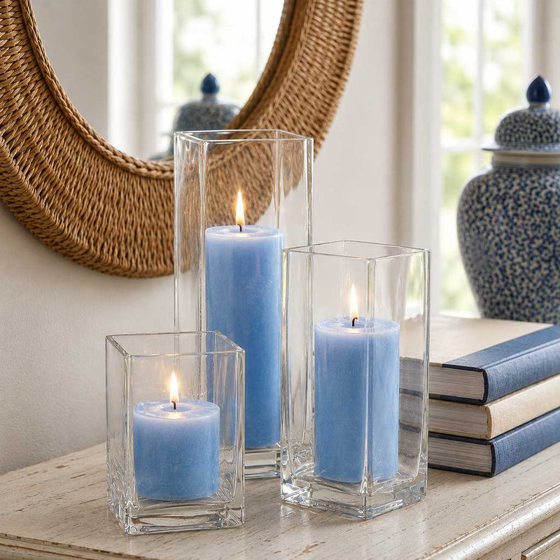 Three lit light blue candle and square holder sets arranged on a console table near a mirror - thumbnail number 6