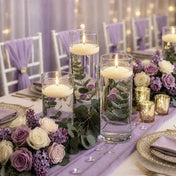 Lit floating candles in cylinder vases with greenery and purple flowers on a table - thumbnail number 4