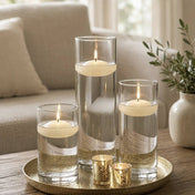 Three lit light ivory floating candles in cylinder vases and two gold votives on a tray - thumbnail number 6