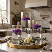 Three glass cylinder vases with lit purple floating candles on a tray with white flowers in a kitchen - thumbnail number 7