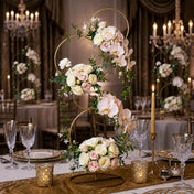 Gold 4-tier hoop stand adorned with blush roses, orchids, and greenery on a wedding table - thumbnail number 8