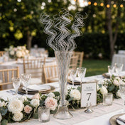 Silver sparkle curly ting stems in a glass vase on an outdoor wedding table - thumbnail number 6