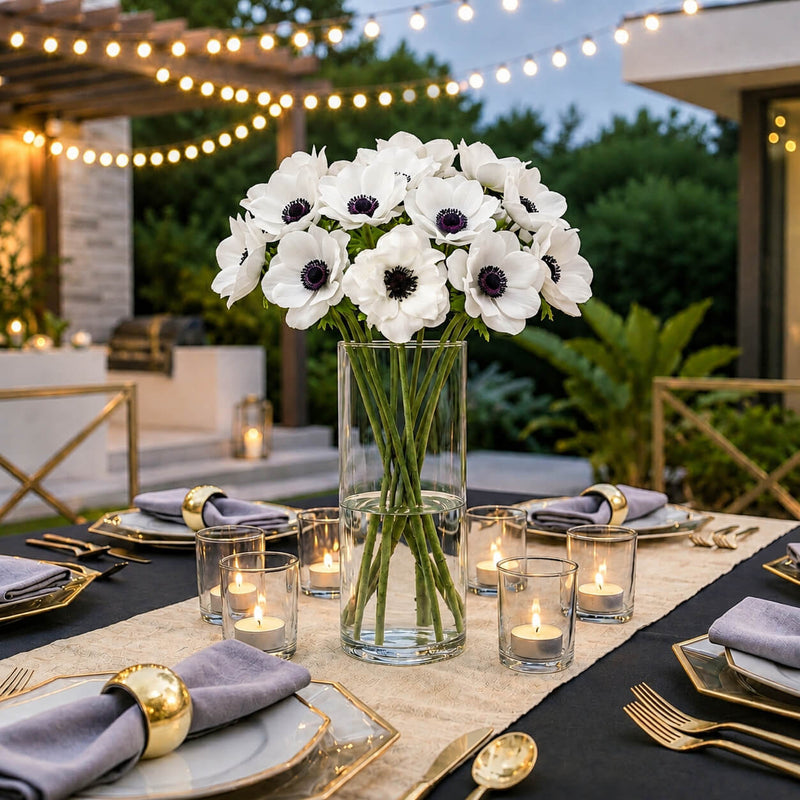 White anemone flowers in a glass cylinder vase on an outdoor dining table - thumbnail number 5