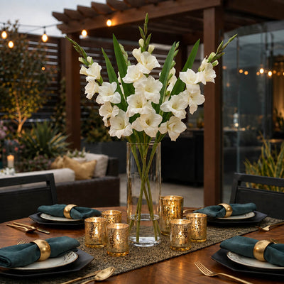 White gladiolus flowers in a glass vase on a lit outdoor dining table - thumbnail number 5