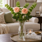 Peach garden roses in a glass vase placed on a coffee table in a living room - thumbnail number 7