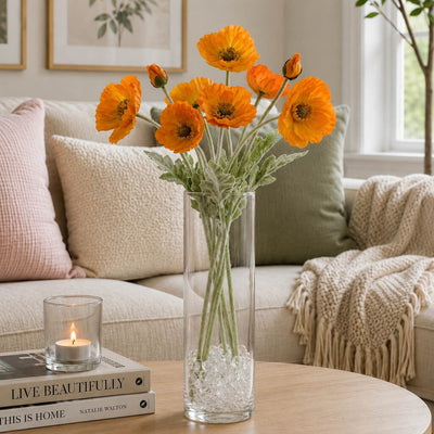 Orange poppy flower sprays in a tall glass vase on a coffee table with books and a candle - thumbnail number 8