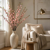 45" pink cherry blossom branches in a cream vase beside a cozy armchair - thumbnail number 7