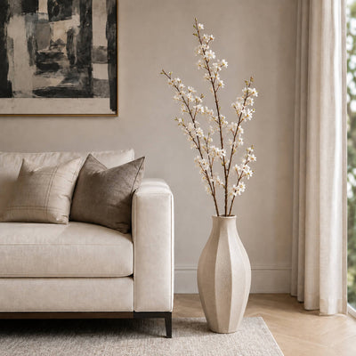 White cherry blossom branches in a textured vase beside a beige sofa - thumbnail number 6