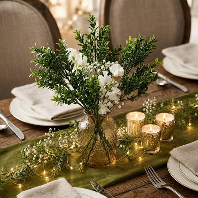 Green boxwood sprays with white flowers in a glass vase on a table - thumbnail number 3