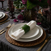 Banana leaf napkin ring holding a white napkin on layered plates - thumbnail number 6