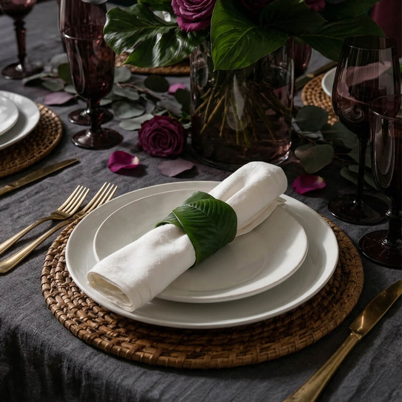 Banana leaf napkin ring holding a white napkin on layered plates - thumbnail number 6