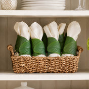 Banana leaf napkin rings holding white napkins inside a woven basket on a shelf - thumbnail number 8