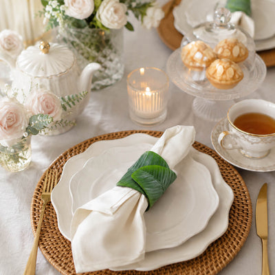 Banana leaf napkin ring holding a white napkin on layered white plates - thumbnail number 10