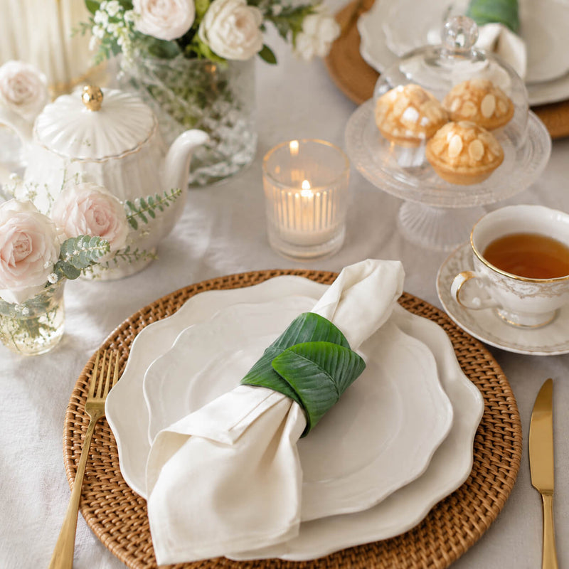 Banana leaf napkin ring holding a white napkin on layered white plates - thumbnail number 10