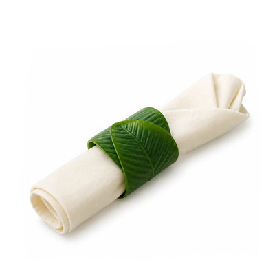 Banana leaf napkin ring holding a folded white napkin isolated on white - thumbnail number 2