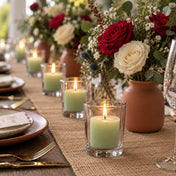 Green votive candles in clear glass holders lined up on a rustic tablescape with floral centerpieces - thumbnail number 7