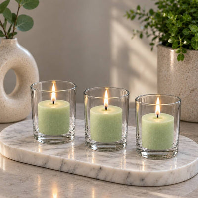 Three lit green votive candles in clear glass holders on an oval marble tray with decor - thumbnail number 10
