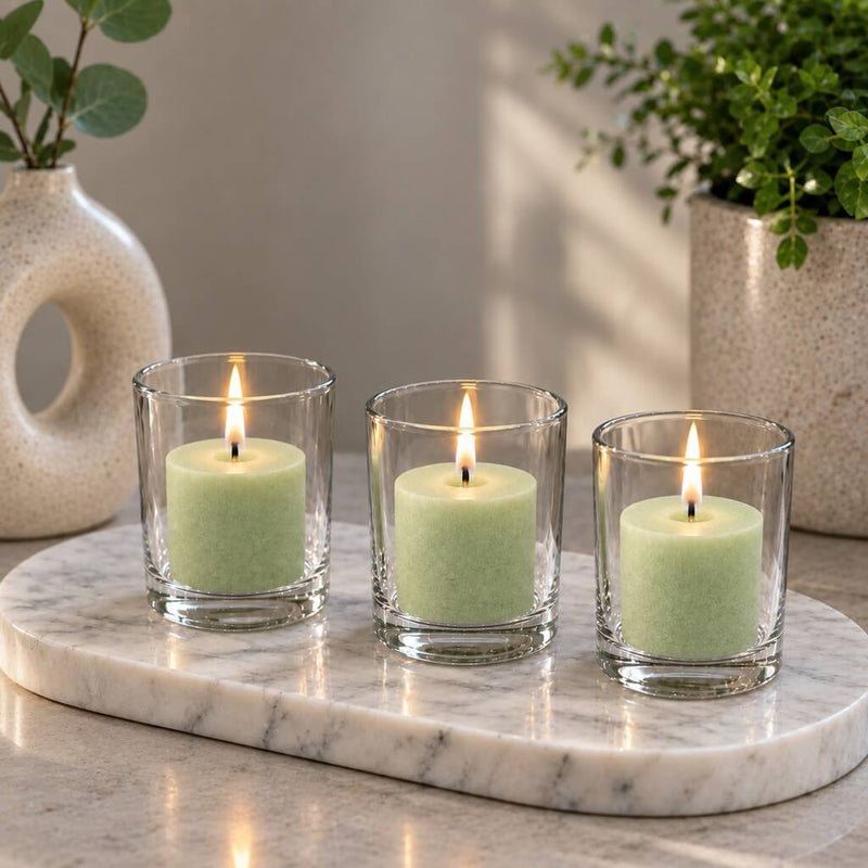 Three lit green votive candles in clear glass holders on an oval marble tray with decor - thumbnail number 10