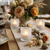 Decorative table setting with candles, flowers, and stones on a textured tablecloth. - thumbnail number 5