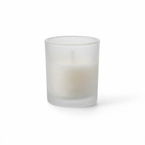 Frosted glass votive holder with white candle on white background