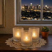 Frosted sparkle votive holders glowing on a table with city lights background - thumbnail number 6