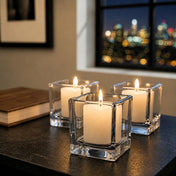 Three pillar candles in square glass holders on table by city window at night - thumbnail number 7