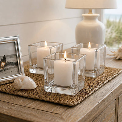 Lit white candles in square glass holders on coastal-style wooden table - thumbnail number 8