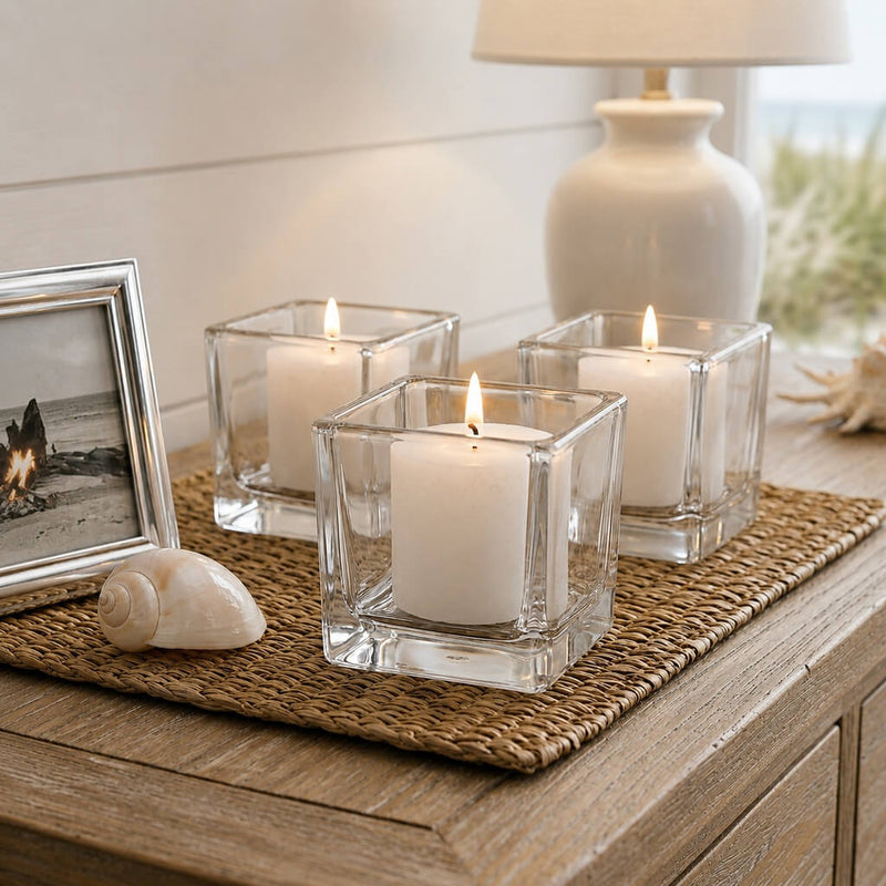 Lit white candles in square glass holders on coastal-style wooden table - thumbnail number 8