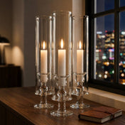White vigil candles in tall glass holders beside window with city lights at night - thumbnail number 6