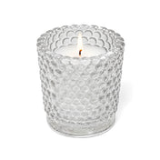 A lit white candle inside a clear hobnail glass votive holder on a solid white background - thumbnail number 3
