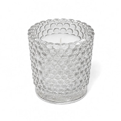 An unlit white candle inside a clear hobnail glass votive holder on a solid white background - thumbnail number 2