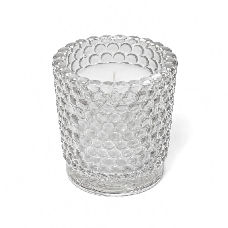 An unlit white candle inside a clear hobnail glass votive holder on a solid white background - thumbnail number 2
