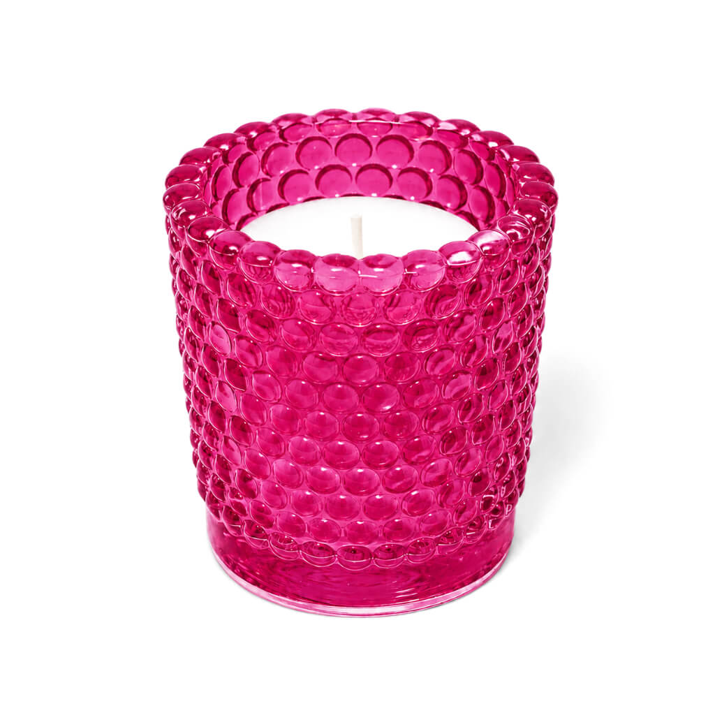 Pink hobnail glass votive holder with white candle on white background