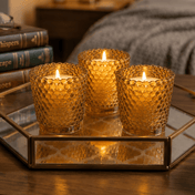 Three amber hobnail votive candles on mirrored tray beside books and cozy bed - thumbnail number 8