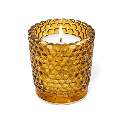 Amber hobnail glass votive candle holder with lit white candle on white background - thumbnail number 3