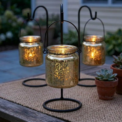 Three lit gold mercury glass hanging holders on a burlap mat beside potted succulents outdoors - thumbnail number 7