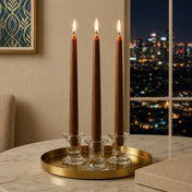 Three lit brown taper candles on a gold tray by a city window at night - thumbnail number 6