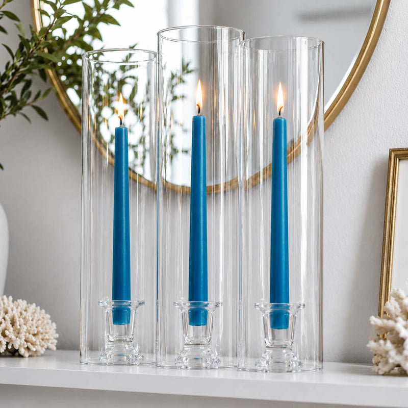 Blue taper candles in tall glass hurricane holders on white shelf - thumbnail number 7